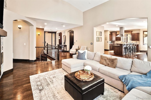 living area featuring dark wood-type flooring, recessed lighting, arched walkways, and baseboards