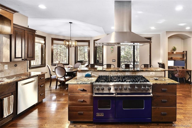 kitchen with light stone counters, dark wood-style flooring, stainless steel appliances, tasteful backsplash, and island range hood