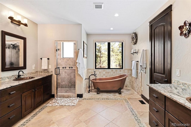 full bath featuring a shower stall, two vanities, visible vents, and a sink