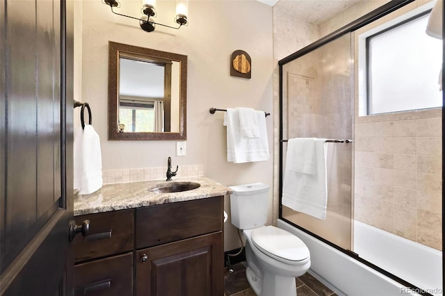 bathroom featuring combined bath / shower with glass door, toilet, and vanity