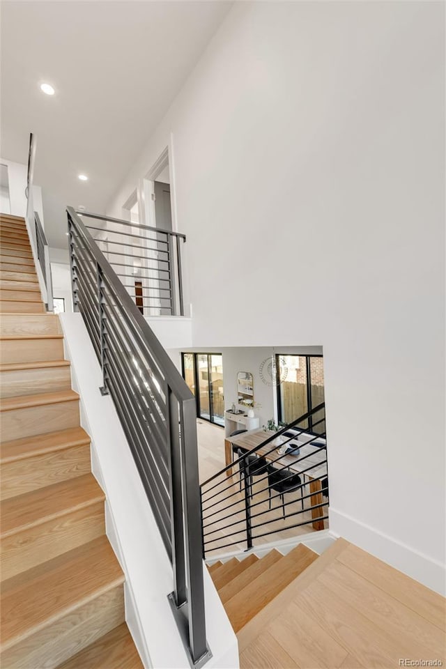 stairs featuring a towering ceiling and hardwood / wood-style floors