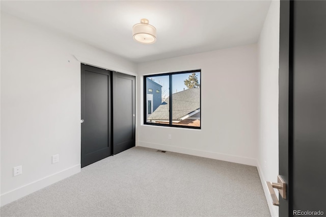 unfurnished bedroom with light carpet and a closet