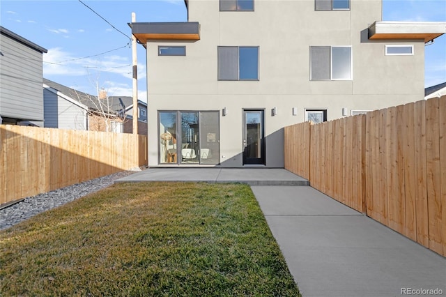 back of property with a lawn and a patio area