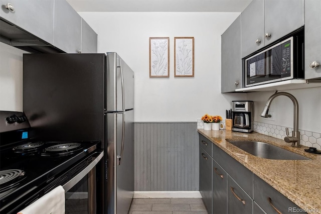 kitchen featuring light stone counters, stainless steel electric range oven, gray cabinetry, and sink