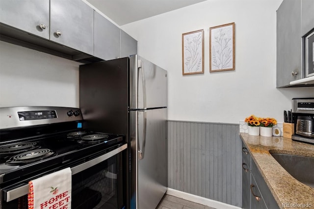 kitchen featuring gray cabinetry, stainless steel appliances, and light stone counters