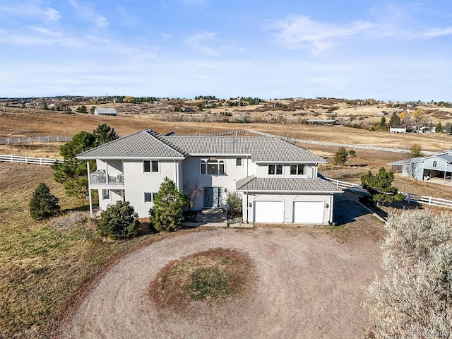 view of front of property featuring a balcony, a garage, and a rural view