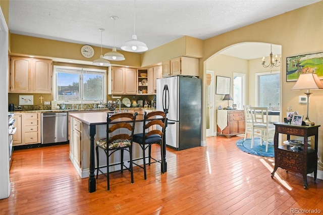 kitchen featuring a kitchen island, stainless steel appliances, a kitchen bar, decorative light fixtures, and light wood-type flooring