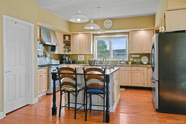 kitchen with a kitchen island, a breakfast bar, light brown cabinets, stainless steel appliances, and wall chimney range hood