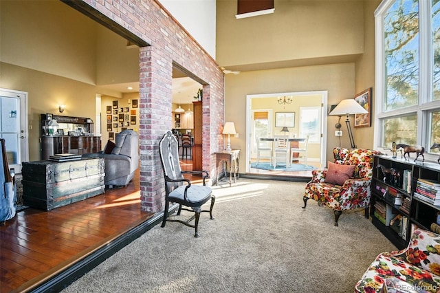 living area featuring ornate columns, carpet, a high ceiling, and a notable chandelier