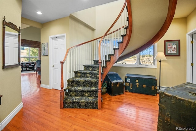 stairs featuring hardwood / wood-style flooring, a baseboard heating unit, and a healthy amount of sunlight