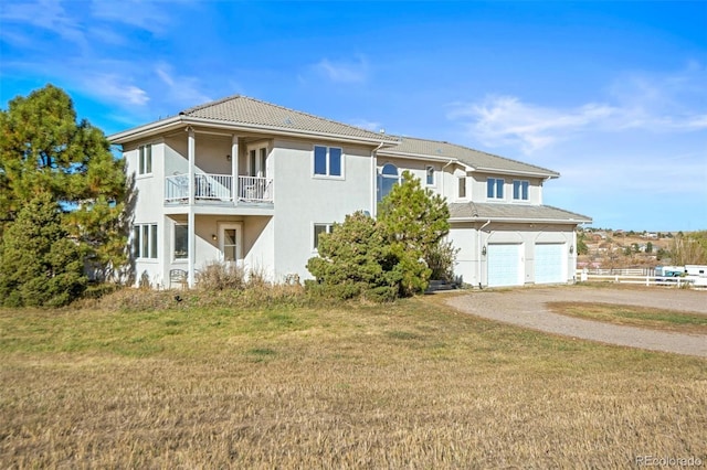 view of front of house with a balcony, a garage, and a front lawn