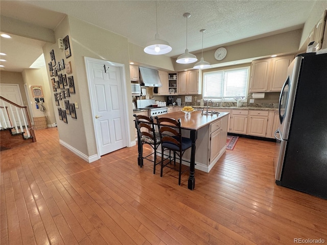 595 W Oak Hill Ln, Castle Rock, CO 80108 - kitchen with appliances with stainless steel finishes, a breakfast bar, a center island with sink, a sink, and wall chimney exhaust hood