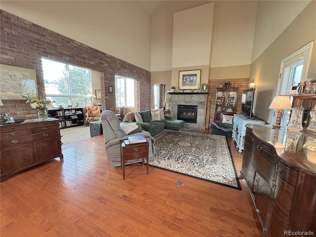 595 W Oak Hill Ln, Castle Rock, CO 80108 - living room featuring high vaulted ceiling, a tile fireplace, light wood-type flooring, and brick wall
