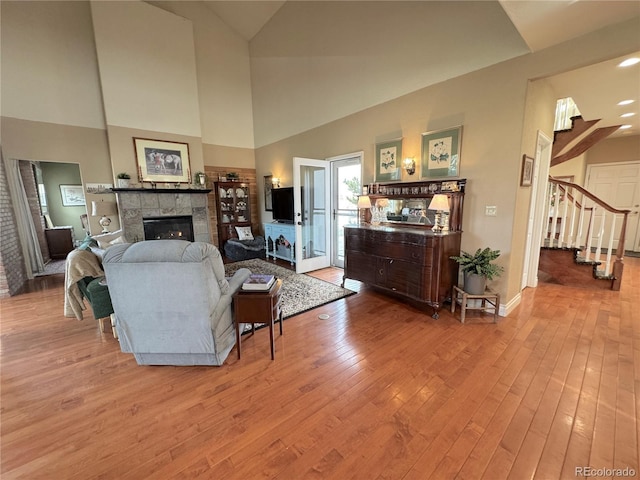 595 W Oak Hill Ln, Castle Rock, CO 80108 - living area with a tile fireplace, stairs, wood finished floors, high vaulted ceiling, and baseboards