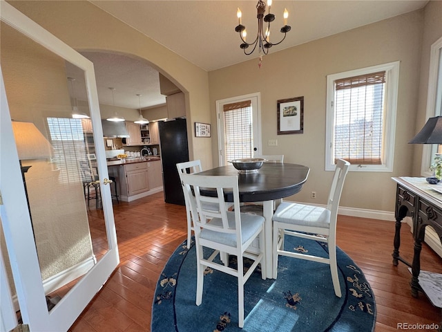 595 W Oak Hill Ln, Castle Rock, CO 80108 - dining area with arched walkways, hardwood / wood-style flooring, baseboards, and a chandelier