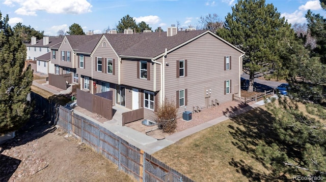 rear view of property with central AC, fence, a lawn, and a chimney