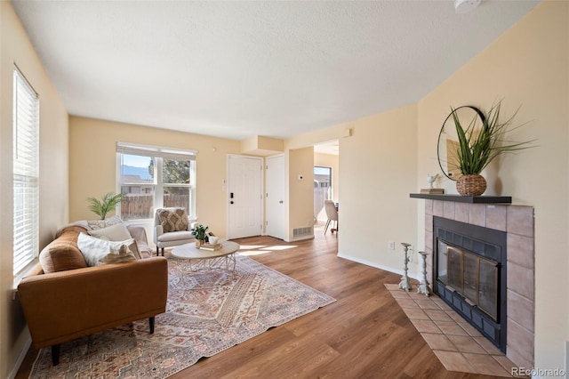 living room with visible vents, baseboards, wood finished floors, and a fireplace
