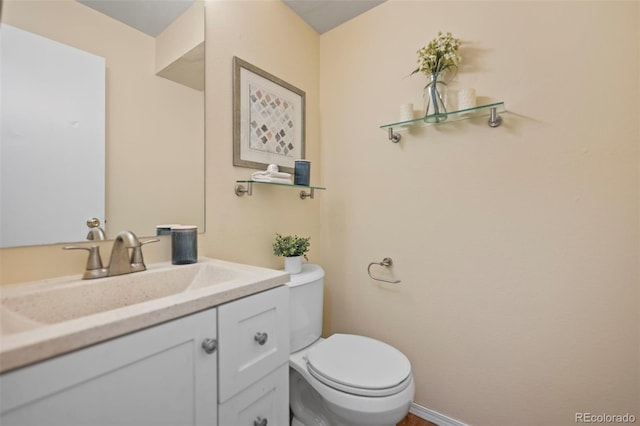 bathroom featuring toilet, vanity, and baseboards