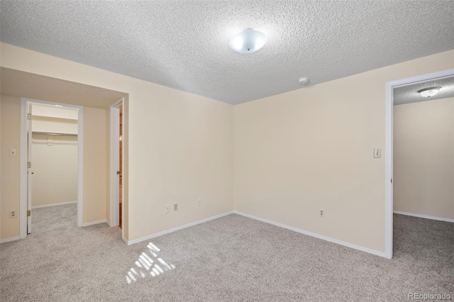 unfurnished bedroom featuring carpet floors, a walk in closet, and a textured ceiling