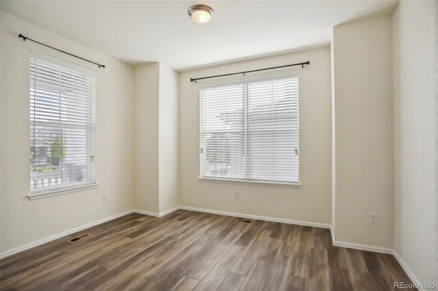 empty room with dark wood-type flooring and plenty of natural light