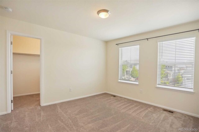 unfurnished bedroom featuring carpet, a closet, and a spacious closet