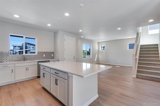 kitchen featuring sink, dishwasher, a center island, light hardwood / wood-style floors, and white cabinets