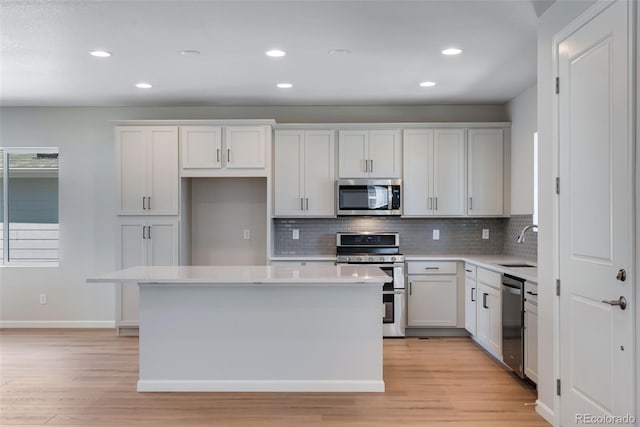 kitchen with appliances with stainless steel finishes, a center island, sink, and white cabinets