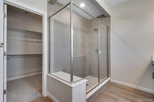 bathroom with a shower with shower door and wood-type flooring