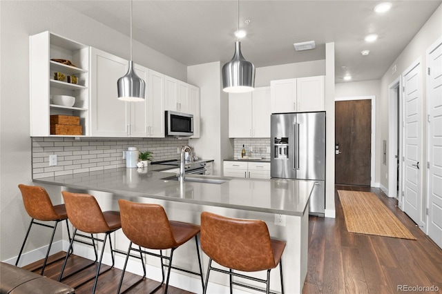 kitchen with a sink, open shelves, appliances with stainless steel finishes, a peninsula, and dark wood-style flooring