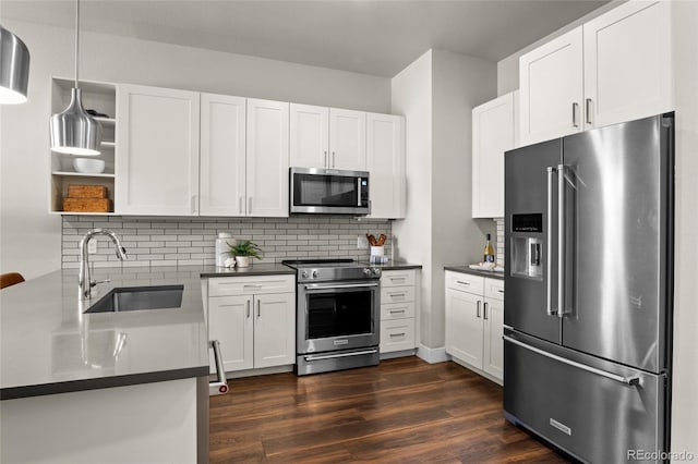 kitchen featuring a sink, stainless steel appliances, dark countertops, and dark wood finished floors