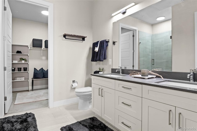 bathroom featuring double vanity, a stall shower, toilet, and a sink