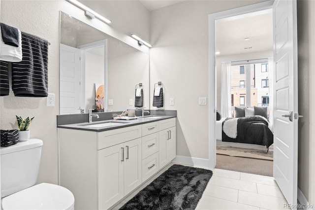 full bathroom with toilet, ensuite bathroom, a sink, tile patterned flooring, and double vanity