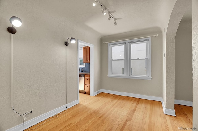 1208 S Elizabeth St, Denver, CO 80210 - interior space featuring arched walkways, rail lighting, light wood-type flooring, and baseboards