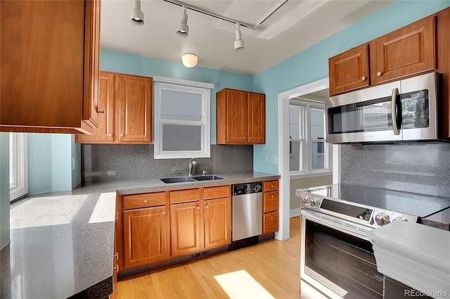 1208 S Elizabeth St, Denver, CO 80210 - kitchen featuring appliances with stainless steel finishes, a sink, brown cabinetry, rail lighting, and decorative backsplash