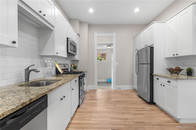 328 E Dakota Ave, Denver, CO 80209 - kitchen featuring stainless steel appliances, a sink, light wood-type flooring, white cabinets, and tasteful backsplash