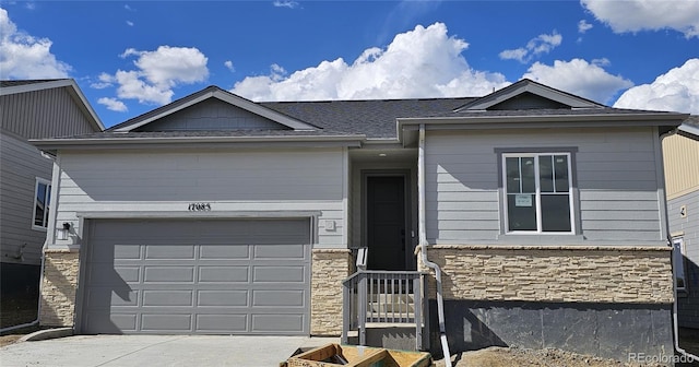 ranch-style house with concrete driveway, stone siding, and an attached garage