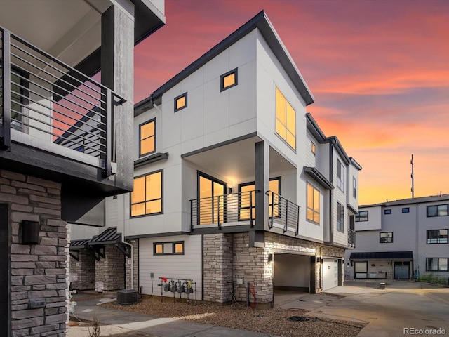 2050 S Holly St Unit 1, Denver, CO 80222 - exterior space featuring stone siding, a garage, concrete driveway, and a balcony