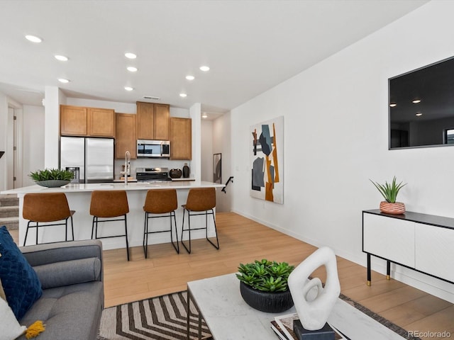 2050 S Holly St Unit 1, Denver, CO 80222 - kitchen featuring appliances with stainless steel finishes, light wood-style floors, brown cabinetry, light countertops, and recessed lighting