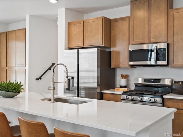 2050 S Holly St Unit 1, Denver, CO 80222 - kitchen featuring appliances with stainless steel finishes, light countertops, a breakfast bar area, and brown cabinets