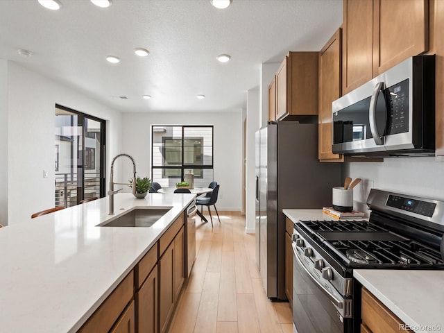 2050 S Holly St Unit 1, Denver, CO 80222 - kitchen with appliances with stainless steel finishes, brown cabinetry, light countertops, light wood-style flooring, and recessed lighting