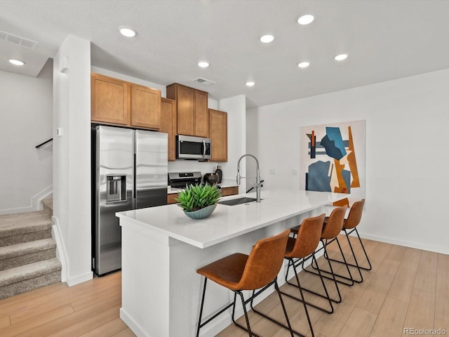 2050 S Holly St Unit 1, Denver, CO 80222 - kitchen with stainless steel appliances, light wood-style flooring, a kitchen breakfast bar, a kitchen island with sink, and recessed lighting