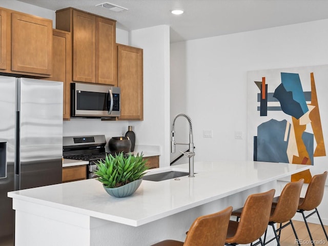 2050 S Holly St Unit 1, Denver, CO 80222 - kitchen featuring stainless steel appliances, a kitchen breakfast bar, light countertops, brown cabinets, and recessed lighting