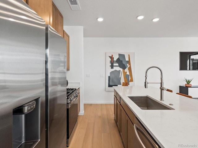 2050 S Holly St Unit 1, Denver, CO 80222 - kitchen featuring appliances with stainless steel finishes, light wood-style flooring, light stone countertops, recessed lighting, and brown cabinetry