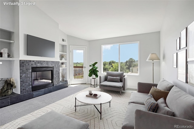 living room with visible vents, built in features, carpet flooring, and a tile fireplace