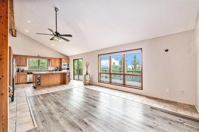 unfurnished living room with high vaulted ceiling, beam ceiling, ceiling fan, and light hardwood / wood-style floors