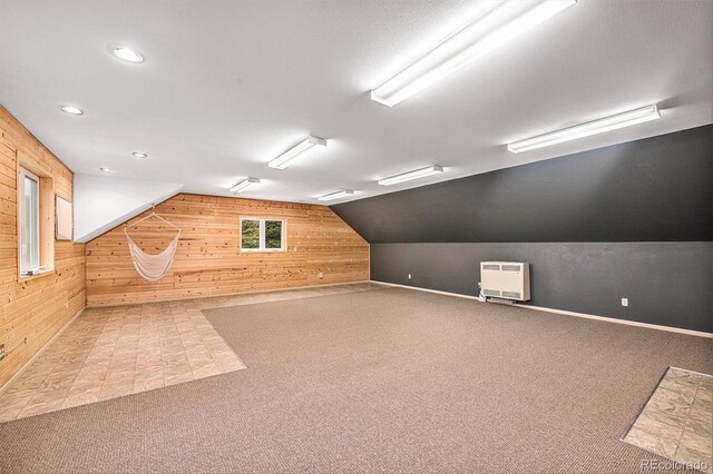 basement featuring light carpet, wooden walls, heating unit, and a textured ceiling