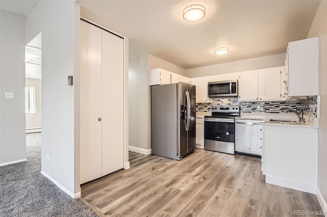 kitchen featuring a sink, white cabinetry, stainless steel appliances, light countertops, and decorative backsplash