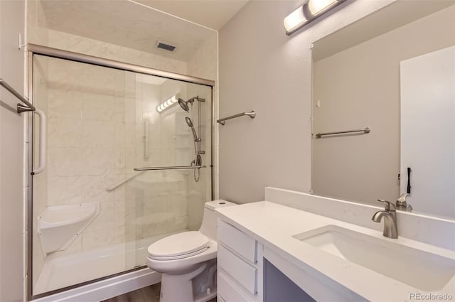 bathroom featuring visible vents, a shower stall, toilet, and vanity