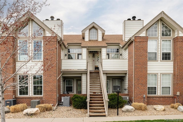 3026 W Prentice Ave Unit H, Littleton, CO 80123 - view of front of house with a chimney, stairway, brick siding, and a shingled roof