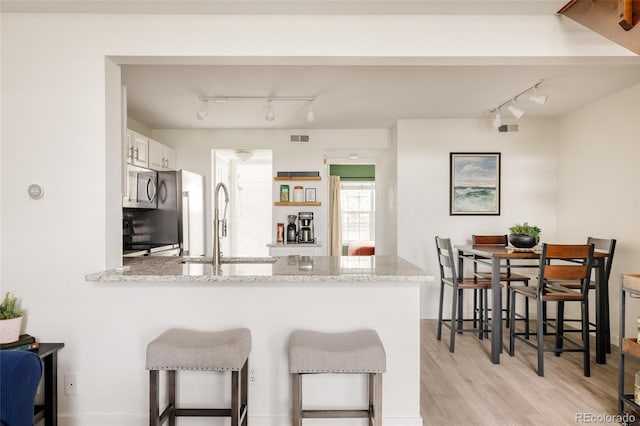 3026 W Prentice Ave Unit H, Littleton, CO 80123 - kitchen featuring rail lighting, stainless steel microwave, a peninsula, light wood-type flooring, and white cabinetry